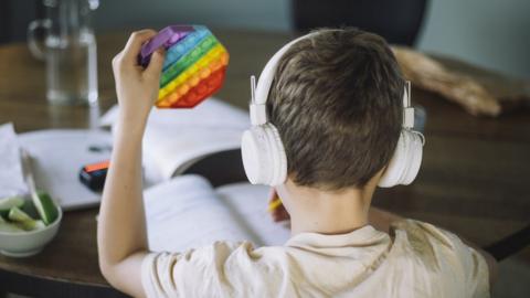 Boy holding push pop toy and wearing headphones