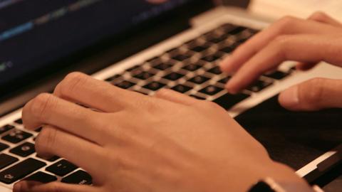 Close up of a pair of hands typing on a keyboard.