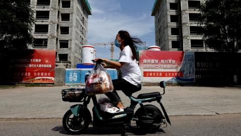 A person rides a scooter past a construction site of residential buildings by Country Garden in Tianjin, China.