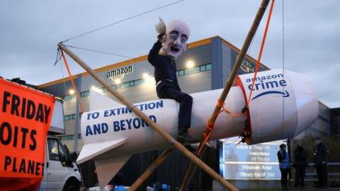 Nicholas Onley on top of a wooden rocket outside Amazon's distribution centre in Tilbury, Essex