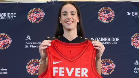 Caitlin Clark holds up her Indiana Fever jersey