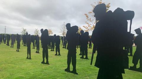 Silhouette statues standing on a grassy space
