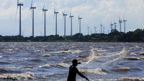 A man fishes in Cocibolca Lake, nearby the Eolo eolic park --inaugurated in May 2013-- in the province of Rivas, about 125 kms south of the capital Managua, on November 4, 2013.