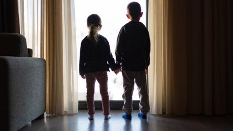 Two children looking out of window