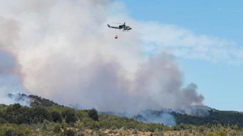 A helicopter flies with water to put out a wildfire at Los Alerces National Park, in Chubut, Argentina January 28, 2024.