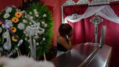 A woman looks into a coffin containing the body of the student Gerald Jose Vasquez, shot dead during clashes with riot police in a church near the National Autonomous University of Nicaragua (UNAN) in Managua,on July 15, 2018