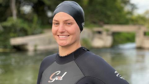 Elle English in a wetsuit next to a river