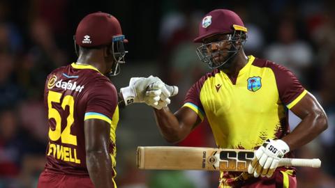 West Indies batters Rovman Powell (left) and Andre Russell (right) punch gloves