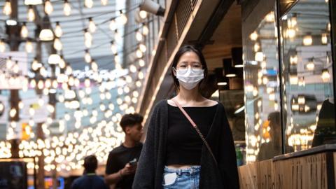 A woman wearing a protective face mask near World Square Sydney, Australia, 18 December 2020