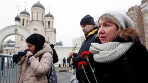 People react outside the Church of the Icon of the Mother of God, ahead of the upcoming funeral of late Russian opposition leader Alexei Navalny, in Moscow