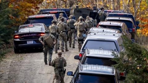 Law enforcement officers search Maine woods.