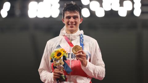 Team GB modern pentathlete Joe Choong smiles on the podium at the Tokyo Olympics while holding up his gold medal