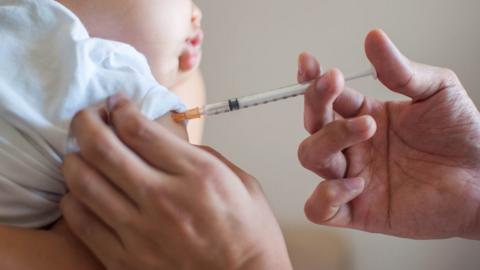 A doctor is injecting a vaccine to a baby boy