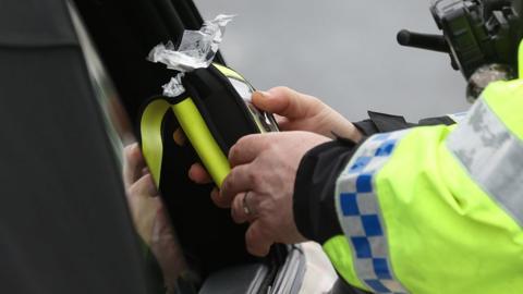 A police officer looking at a breathalyser