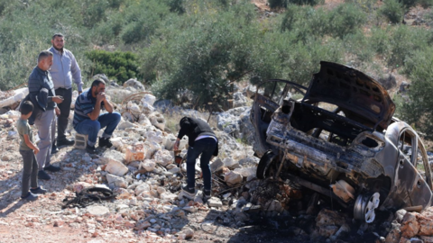 Palestinians inspect a car set on fire by Israeli settlers near the West Bank City of Salfit
