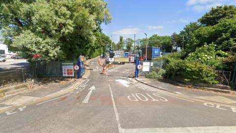 Google street view image of the recycling centre with big green gates and signs