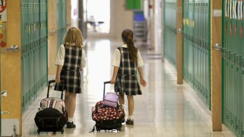 Two girls walk down a school hallway