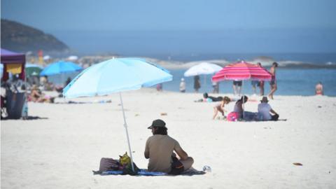 People sunbathing at Bay Beach in Cape Town, South Africa