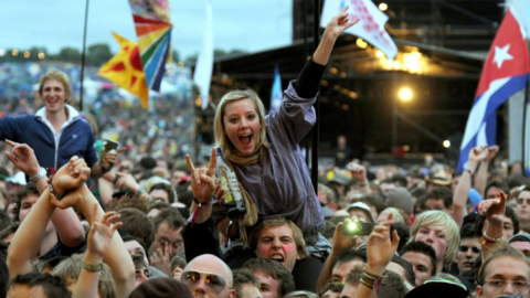 A woman on someone's shoulders at Glastonbury Festival