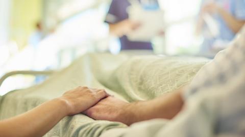 Patients holding hands at hospital bedside