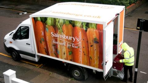 A Sainsbury's delivery van worker unloads shopping from a truck