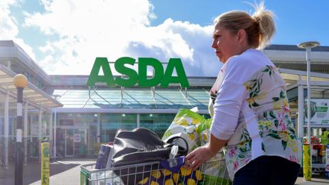 A woman pushes a shopping cart at an Asda superstore at the Gateshead Metrocentre