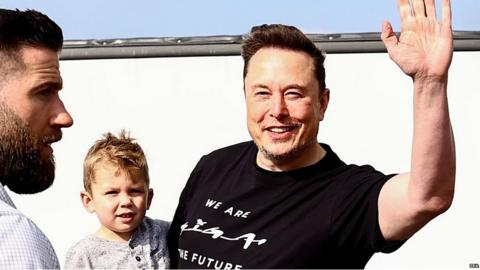 Elon Musk carrying son X AE A-XII and waving to cameras