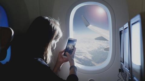 A woman takes a picture out of a plane window