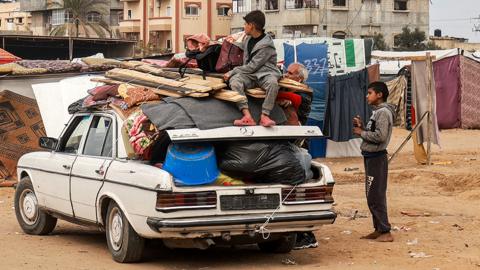 People pack a vehicle before fleeing north towards central Gaza, in Rafah on 13 February