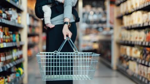 Cropped shot of mother carrying a shopping basket (stock photo)