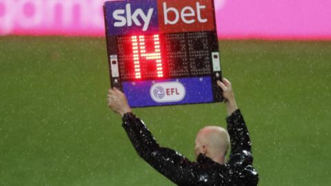 An EFL match official holds up a board indicating 14 minutes of added time