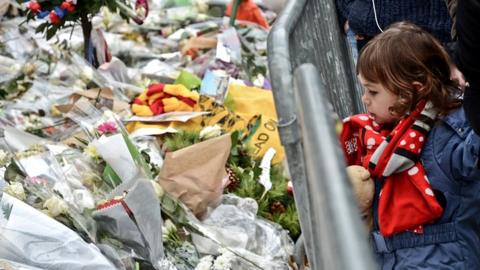 A little girl stands in front of a memorial for the victims of the terrorist attacks at the Bataclan concert hall in Paris, France, 13 December 2015