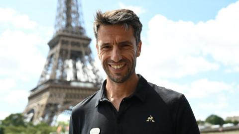 Tony Estanguet smiling in front of the Eiffel Tower.