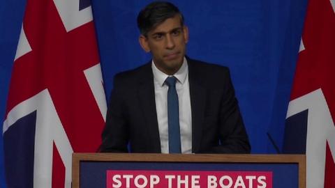 Prime minister Rishi Sunak at a podium that reads "Stop the boats"
