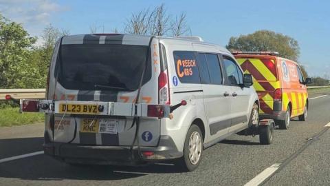 A silver taxi saying Creech Cabs on the window being towed by an RAC track