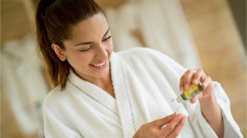 Portrait of a woman cleansing her face with a cotton bud and some beauty product - lifestyle concepts