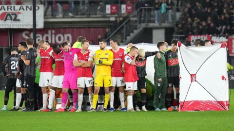 Players of NEC Nijmegen and AZ Alkmaar stand around Bas Dost after he collapses