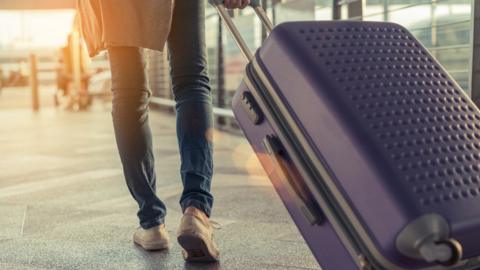 Airline passenger pulling suitcase