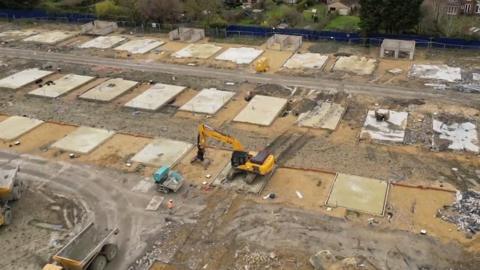 Drone footage shows a digger completing the demolition of new-build homes at Darwin Green in Cambridge