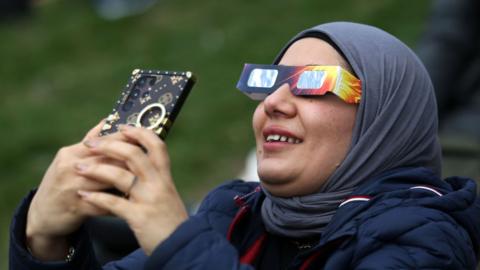 File image of a woman in Toronto watching the 2024 total solar eclipse across North America
