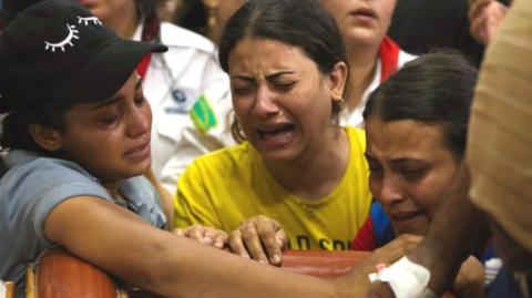 People react during the funeral for victims who died in the Abu Sifine church fire,