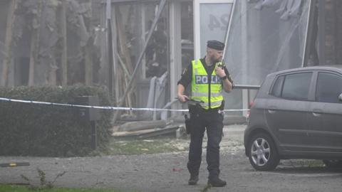 A police officer inspects the site of an explosion in Fullero that killed a 25-year-old woman