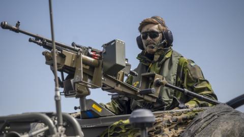 A Swedish soldier mans a machine gun on a boat during NATO military drills n the Baltic Sea, 2022