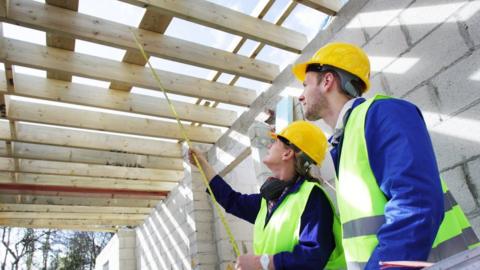 Builders taking measurements in a new house