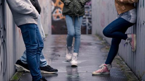 photo of young people from waist down stood on a bridge