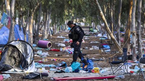 An Israeli security officer inspects the scene of the 7 October attack by Hamas gunmen on the Nova music festival in Reim, Israel (17 October 2023)