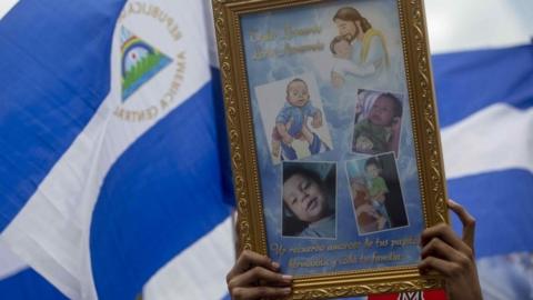 A woman holds a sign with images of children who died in protests during a march , in Managua, Nicaragua, 28 July 2018.