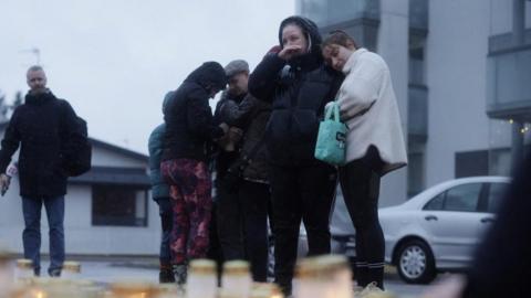 People bring candles and flowers at the Viertola school in Vantaa, Finland, on April 2, 2024