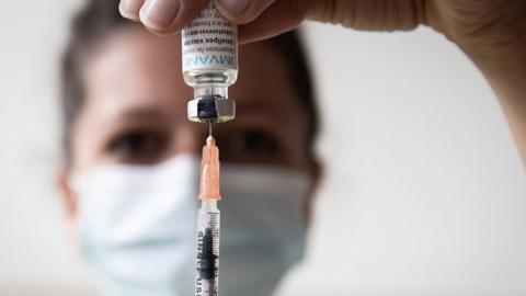 A nurse draws down on a syringe inserted into a monkeypox vaccine vial