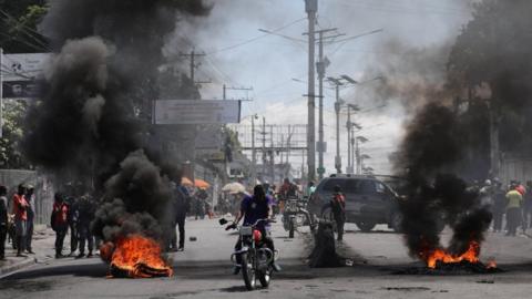 Motorists pass by a burning barricade in Port-au-Prince, Haiti